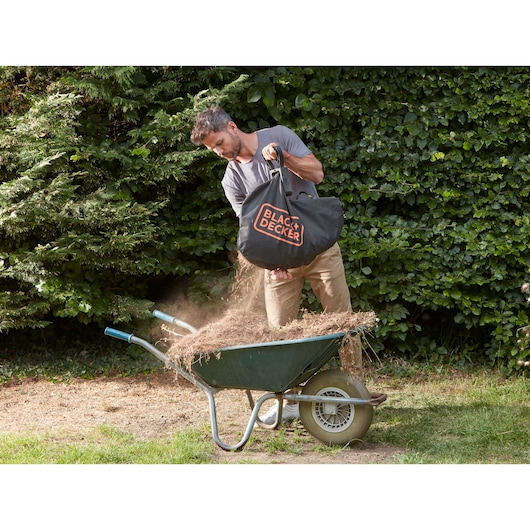 BLACK+DECKER BCBLV36B garden vacuum bag being emptied into a wheelbarrow outdoors.