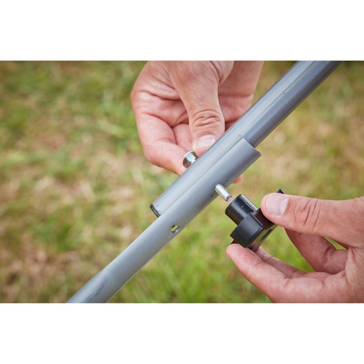 BLACKDECKER BCMW33184L2 lawn mower handle assembly detail, gray metal tubes and black knob outdoors.