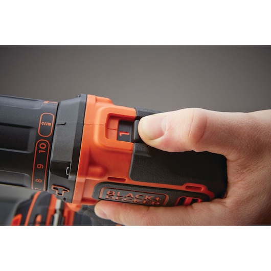 Close-up of a hand adjusting the speed setting on a BLACK+DECKER cordless power drill.