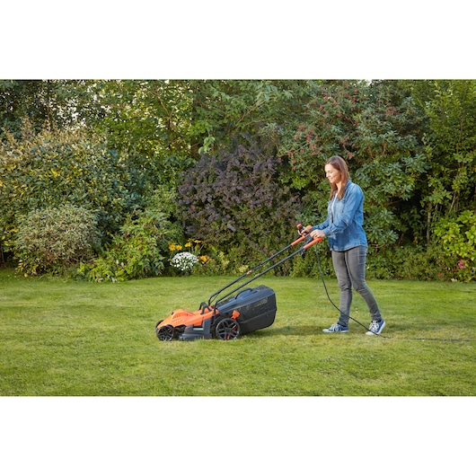 BLACKDECKER BEMW461BH lawn mower in use on grass by person outdoors, orange and black design.