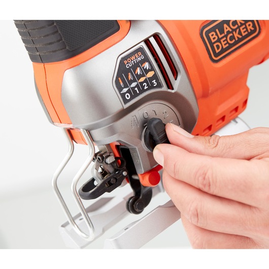 Close-up of a hand adjusting the settings on a BLACK+DECKER power tool, showing control dials and cutting options.