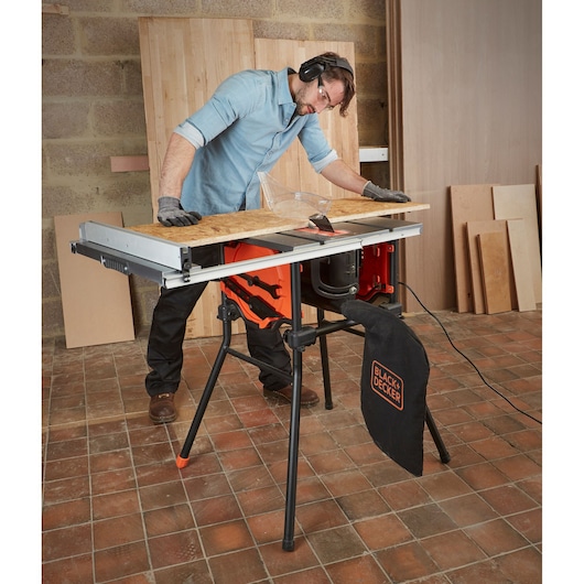 BLACKDECKER BES720 table saw with dust bag, cutting wood in workshop setting.