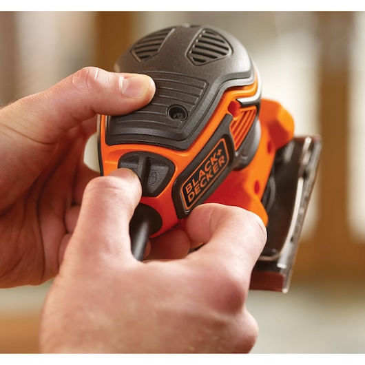 Close-up of hands operating a BLACK+DECKER KA450 power tool, featuring the tool's switch and visible branding.