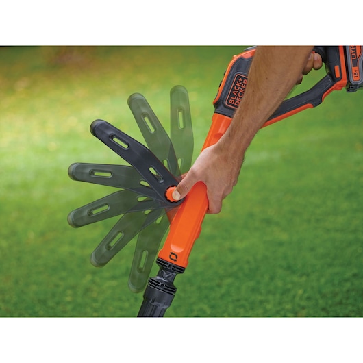 BLACKDECKER STC1820EPC grass trimmer being adjusted by hand outdoors on lawn.