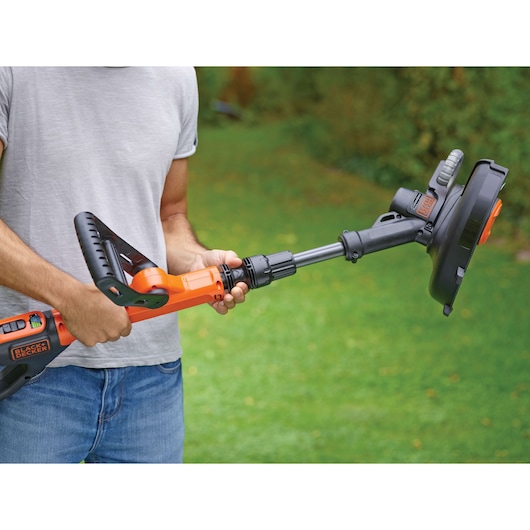 Photo of BLACKDECKER STC1820EPC grass trimmer held by person outdoors, orange and black design.
